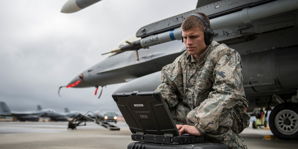 Military Personnel operating computer next to military aircraft